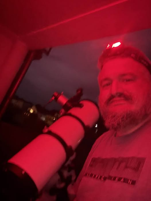 Steve observe le ciel avec son télescope sous éclairage rouge